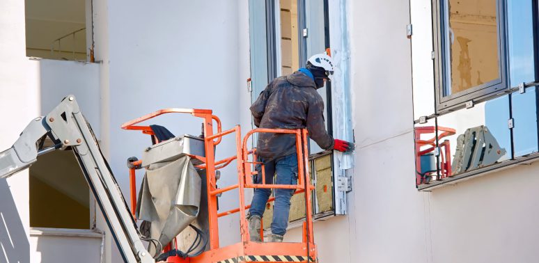 painter in lift bucket caulk